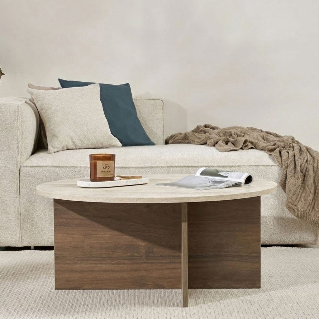 Round coffee table with travertine top and dark wooden base in cross shape.