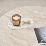 Round coffee table with travertine top and dark wooden base in cross shape.