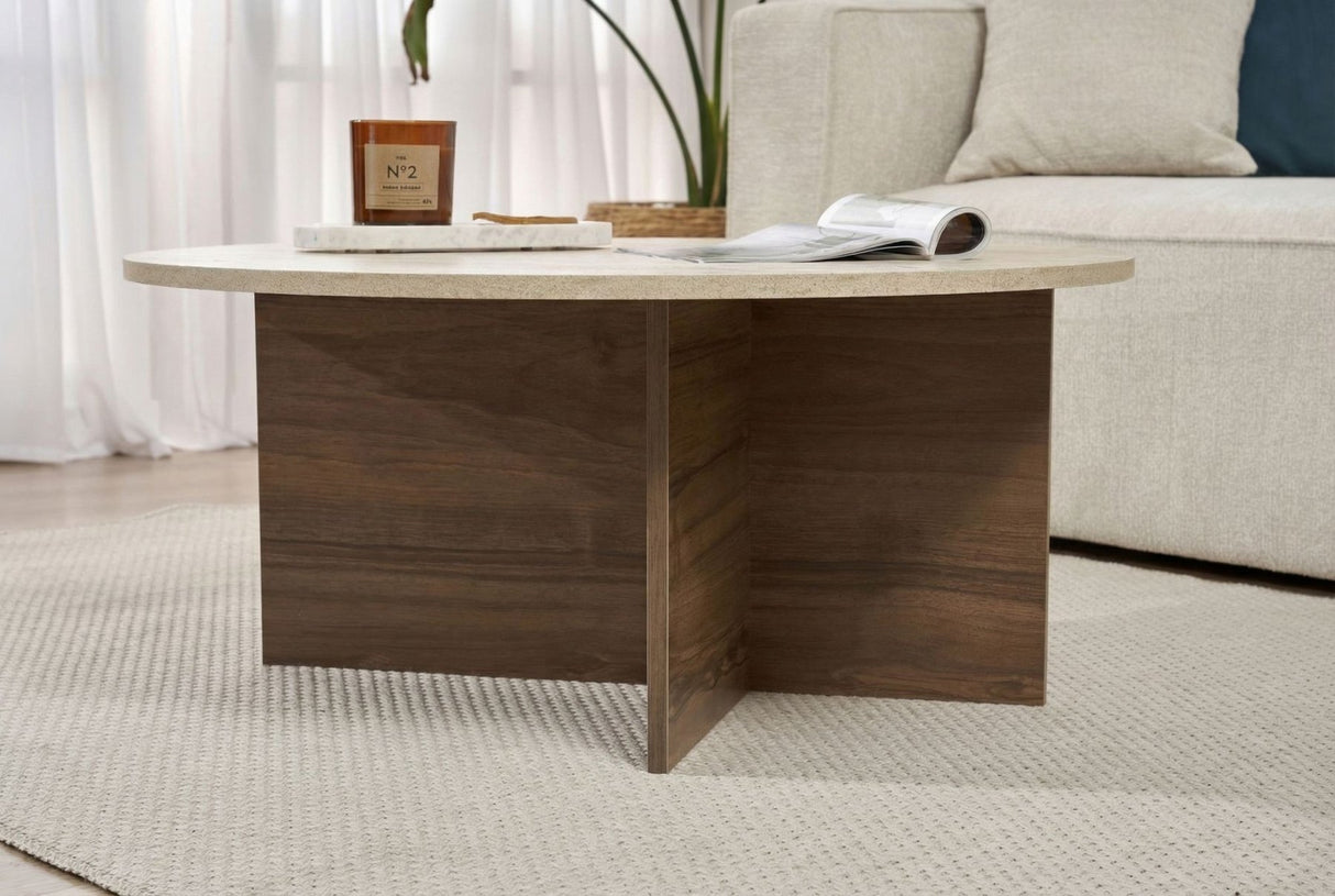 Round coffee table with travertine top and dark wooden base in cross shape.